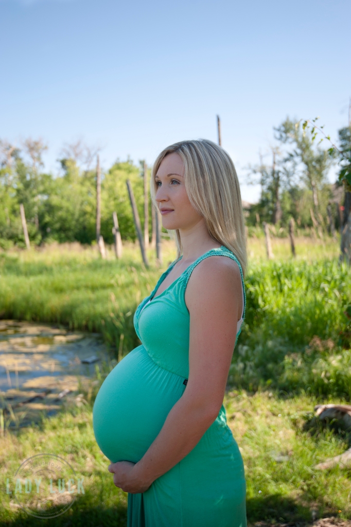 outdoor-maternity-portrait-hand=posed-under-the-belly-eyes-glancing-away-from-the-camera