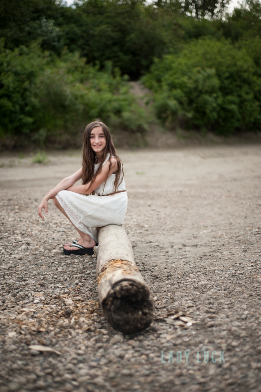 outdoor-glamour-portrait-of-teenager-sitting-on-a-log-beside-the-river-in-edmonton